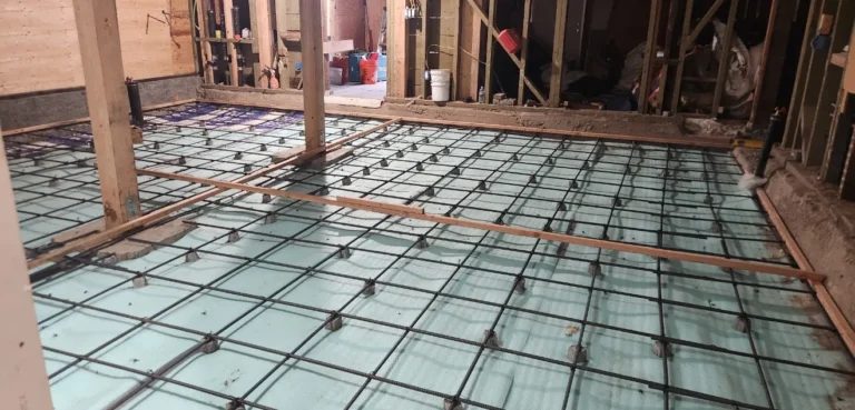 Radiant floor heating PEX tubing and rebar grid laid on insulation before concrete pour in ADU new construction