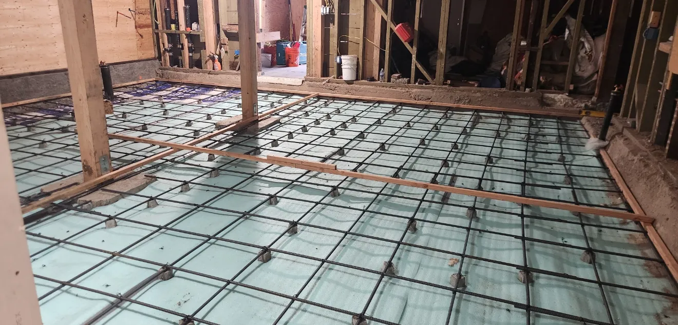 Radiant floor heating PEX tubing and rebar grid laid on insulation before concrete pour in ADU new construction