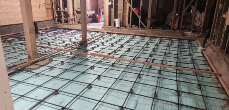 Radiant heating PEX tubing and rebar grid laid on foam insulation before concrete slab pour in an Eichler home renovation