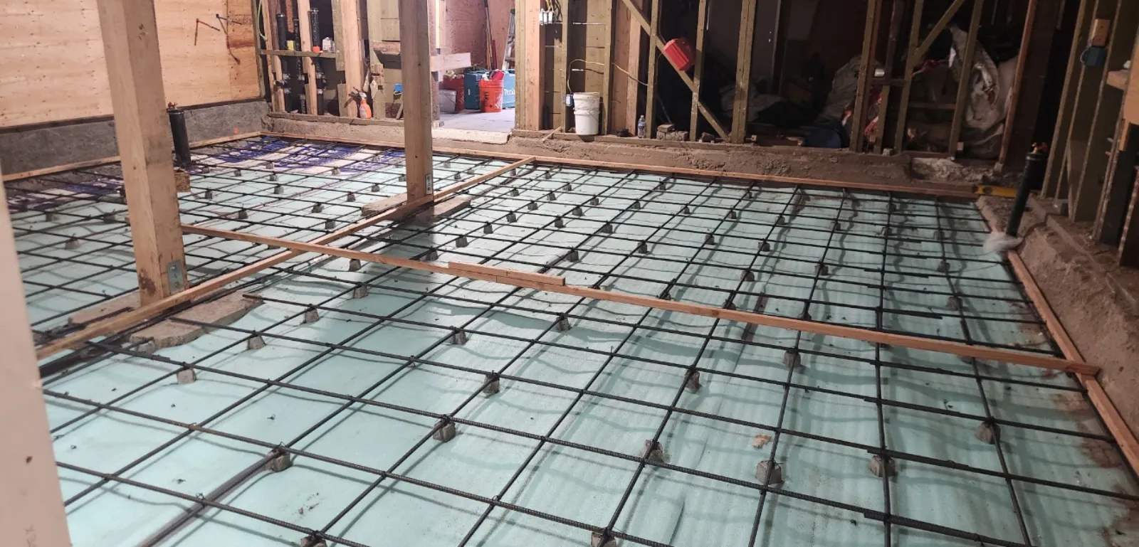 Radiant heating PEX tubing and rebar grid laid on foam insulation before concrete slab pour in an Eichler home renovation